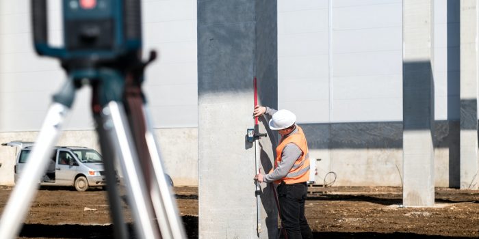 Industrial surveyor on construction site, working with thodolite, gps system and level machine